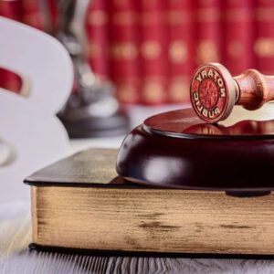 A wooden gavel sitting on top of an old book.