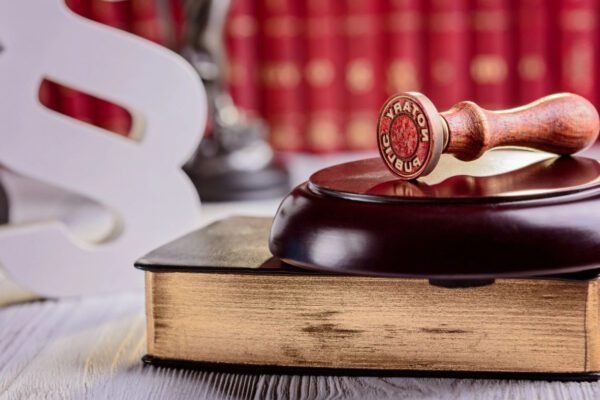 A wooden gavel sitting on top of an old book.