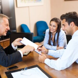 A man handing over paperwork to two people.